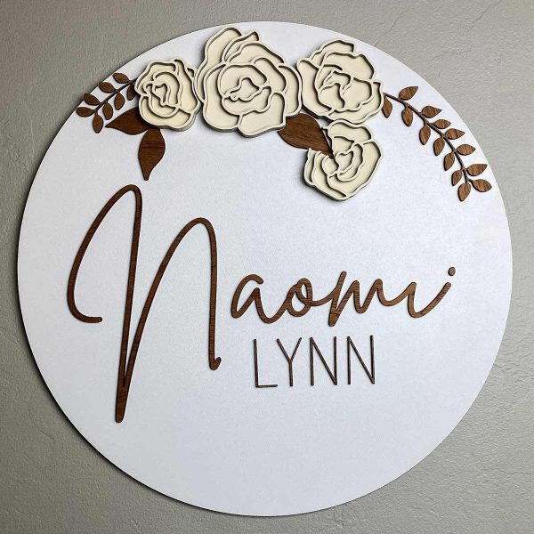 white sign that says Naomi Lynn and has off white flowers